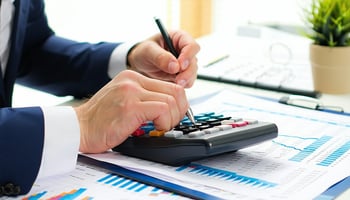 Business owner using a calculator to create an equipment lease budget