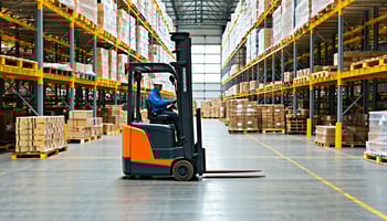 Electric forklift unloading pallet inside warehouse facility