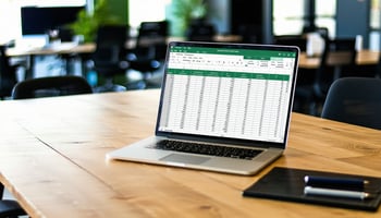 A modern office setting with a sleek wooden desk featuring a laptop open to a spreadsheet, surrounded by an organized and professional workspace.