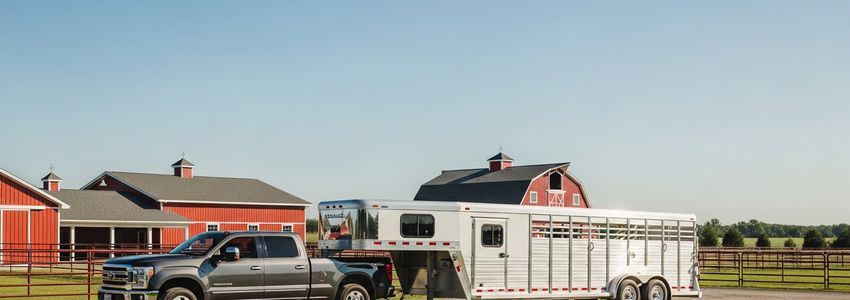 A horse trailer attached to a pickup truck at a farm, representing horse trailer financing options