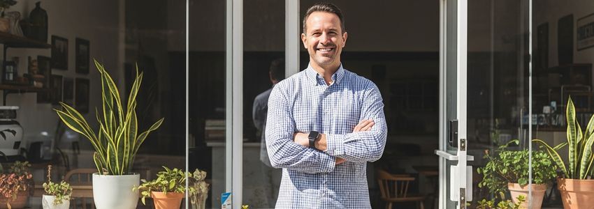 Small business owner standing proudly in front of his California storefront