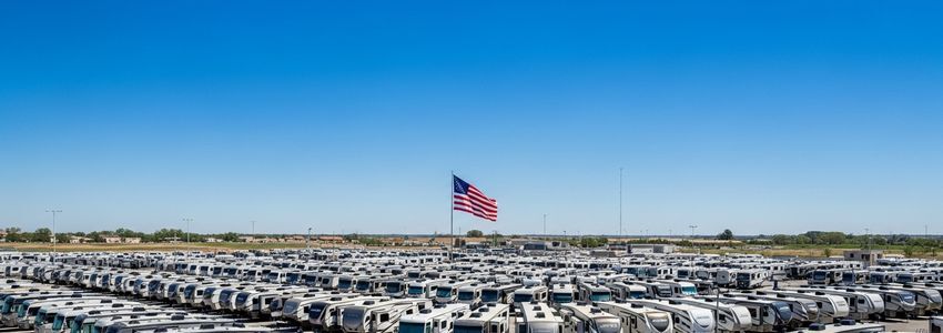 Large RV dealership lot with rows of motorhomes and travel trailers on a sunny day