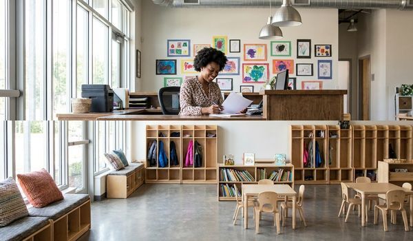 Daycare center director reviewing business financing documents at a modern childcare facility reception desk
