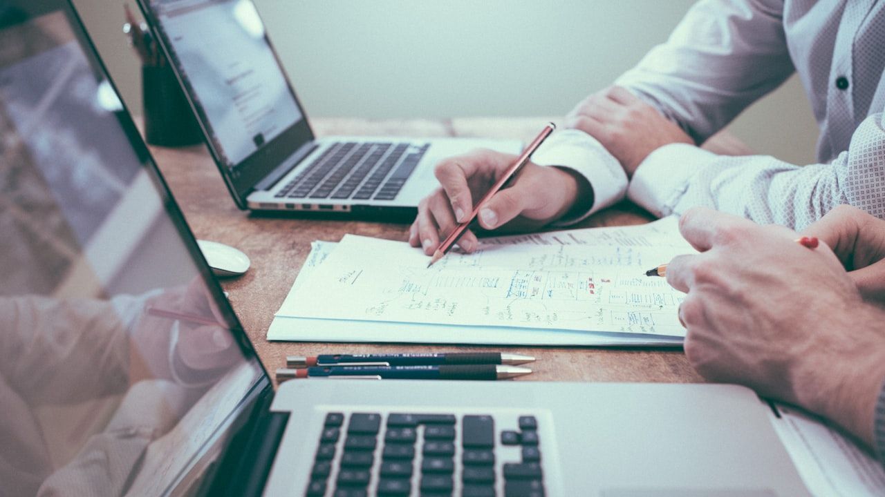 Business professional reviewing equipment financing documents at office desk with industrial equipment visible in background