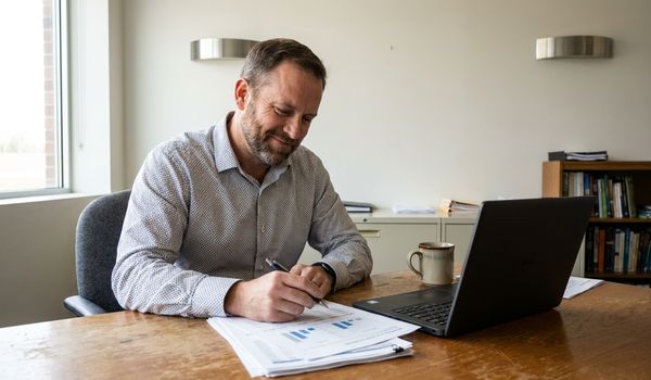 Small business owner reviewing financing paperwork at his office desk while exploring alternative business loans after a bank rejection