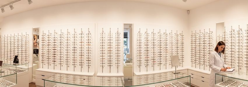 Professional optician reviewing financing documents in a modern optical store with eyeglass frame displays