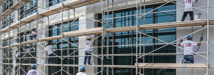 Professional painting contractors using spray equipment on commercial building exterior