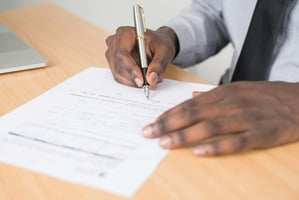 Person writing notes on paper at a desk, symbolizing financial planning and decision-making for small business owners.