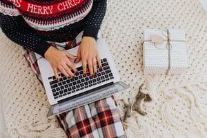 Woman wearing a Christmas outfit working on a laptop while managing seasonal cash flow using revolving credit.