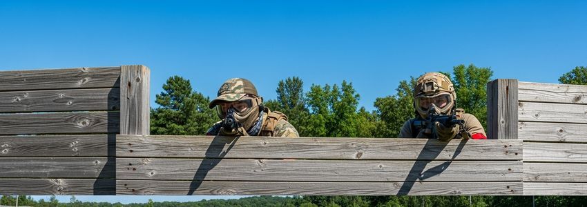 Airsoft players in full tactical gear on a commercial airsoft field facility, representing the outdoor recreational business that benefits from airsoft business loans