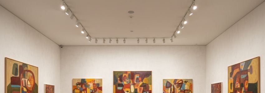 Modern art gallery interior with colorful paintings displayed on white walls and professional gallery lighting