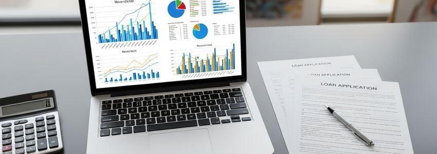 Business loan officer reviewing revenue data and financial charts with a client at a modern office desk