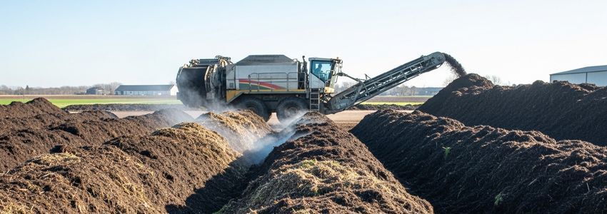 Commercial composting facility operator managing organic waste composting equipment at agricultural facility