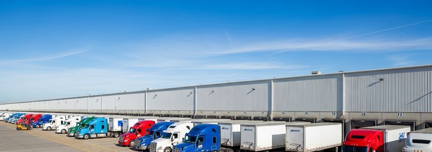 Semi-trucks at a freight distribution center loading dock showing the scale of freight brokerage operations