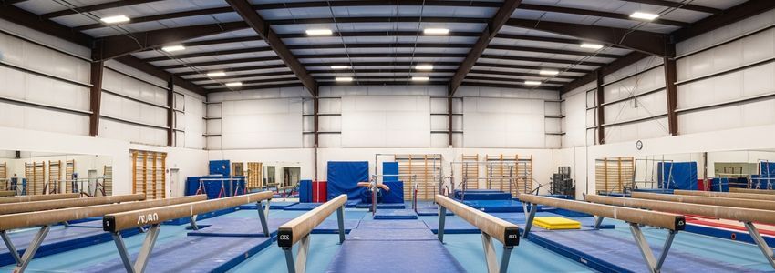Professional gymnastics training facility interior with gymnastics equipment, spring floor system, and balance beams ready for student athletes