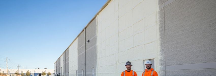 Insulation contractors in safety gear standing outside a commercial building they serviced