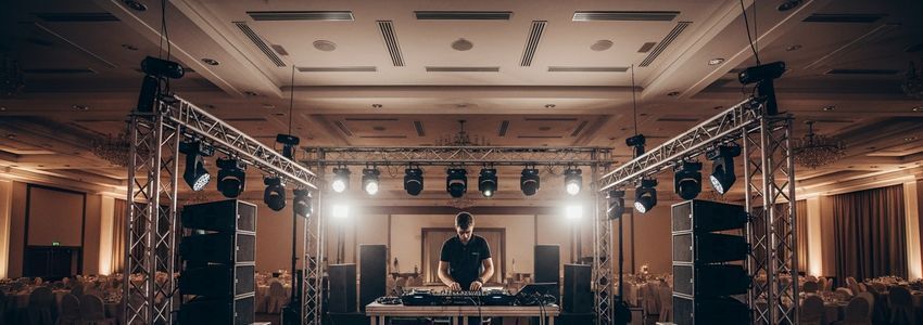 Mobile DJ setting up professional speakers and lighting rig at a venue for an entertainment event