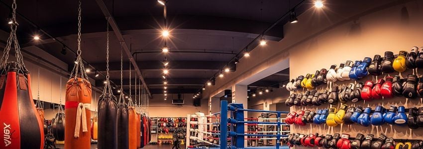 Muay Thai gym owner reviewing business loan documents at desk with training equipment visible in background