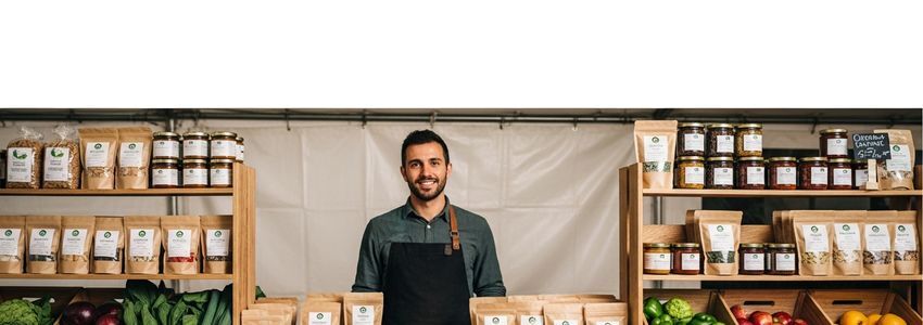 Organic food brand business owner reviewing financing options at a specialty food market display