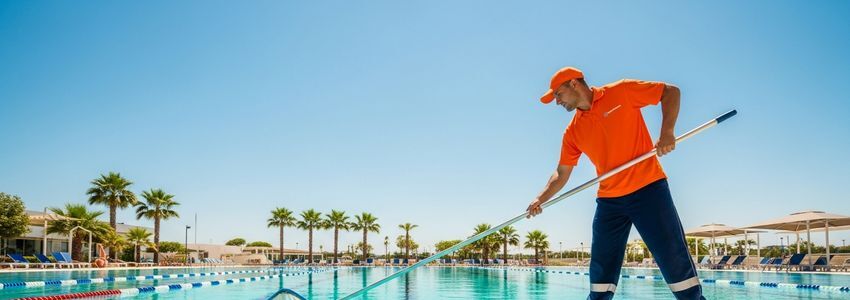 Pool cleaning service technician at work with commercial pool equipment and service vehicle