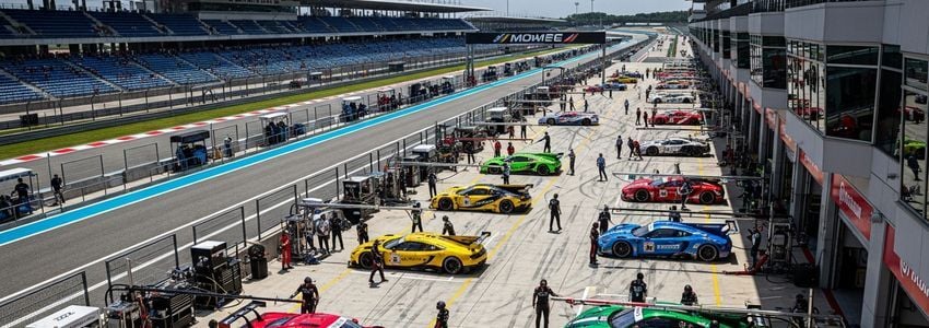 Professional race track facility with multiple racing cars in the pit lane showing motorsports business operations