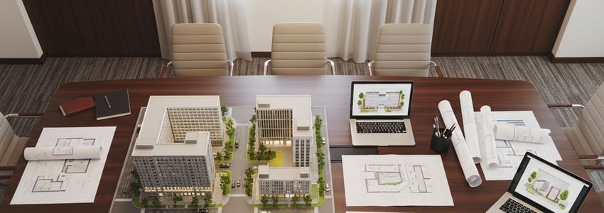 Real estate developer reviewing architectural model and development plans for property financing