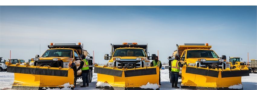 Commercial snow plow trucks lined up at equipment depot ready for winter service