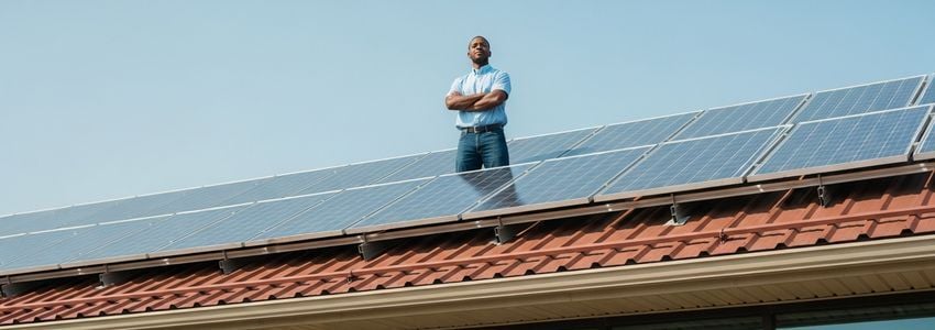 Business owner standing in front of commercial building with solar panels installed on the rooftop