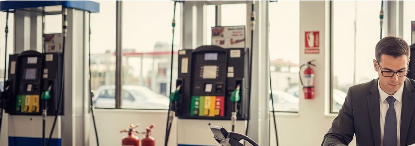 Truck stop business owner reviewing financing options at a fuel station with dispensers visible in the background