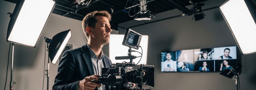 A professional videographer operating cinema camera in commercial studio setting for video marketing production