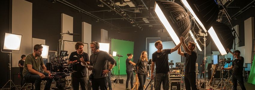 Professional video production crew filming on a studio set with cinema cameras and professional lighting equipment