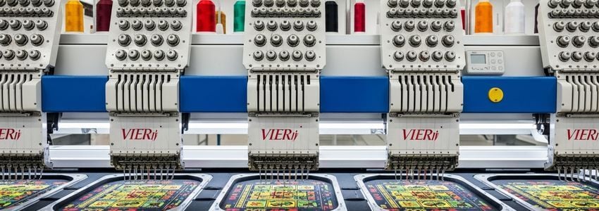 Commercial multi-head embroidery machines actively stitching colorful designs in a professional embroidery shop
