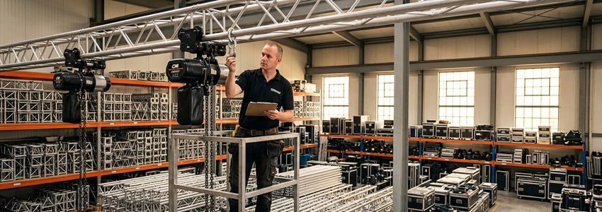 Event production professional inspecting truss and rigging equipment inventory in a warehouse