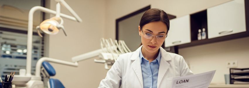 Dentist reviewing dental practice loan documents at dental office desk
