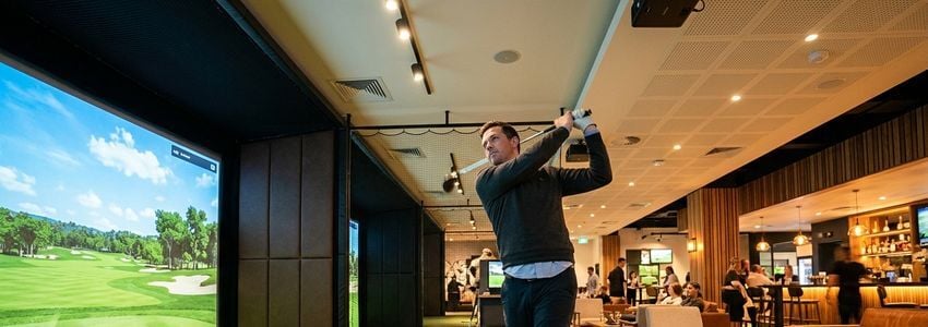 Business owner reviewing golf simulator and batting cage equipment financing plans at an indoor sports entertainment facility