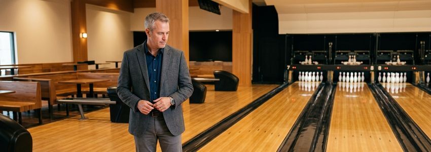 Business owner inspecting a newly refurbished bowling lane in a modern bowling center