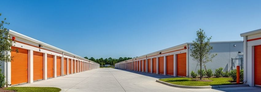 Modern self-storage facility with orange roll-up doors and clean driveways