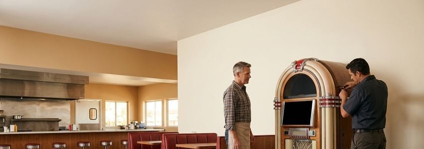 Business owner and technician installing a jukebox in a restaurant setting